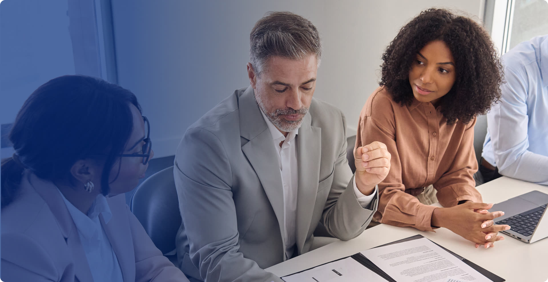 Senior technology and business leaders reviewing documents together at a boardroom table