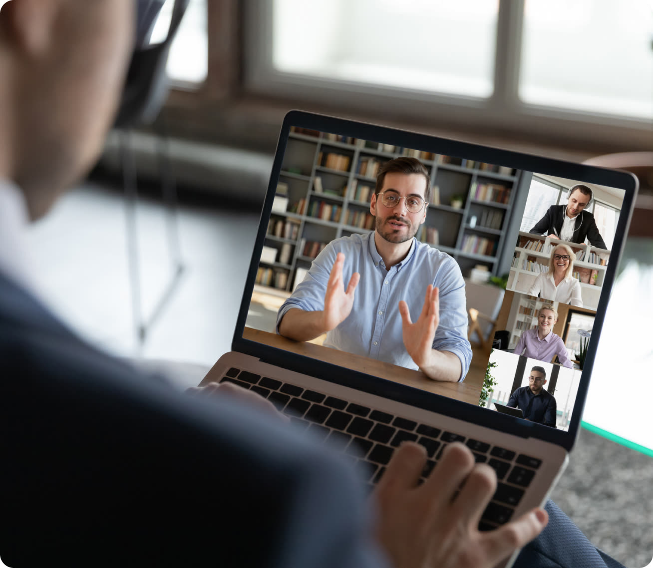 Learner holding a laptop showing a live video session with an instructor and participants